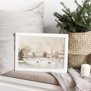 May include: A framed watercolour painting depicting a winter scene with people ice skating on a frozen lake in front of a small town. The painting features a soft, muted colour palette with shades of brown, grey, and white.