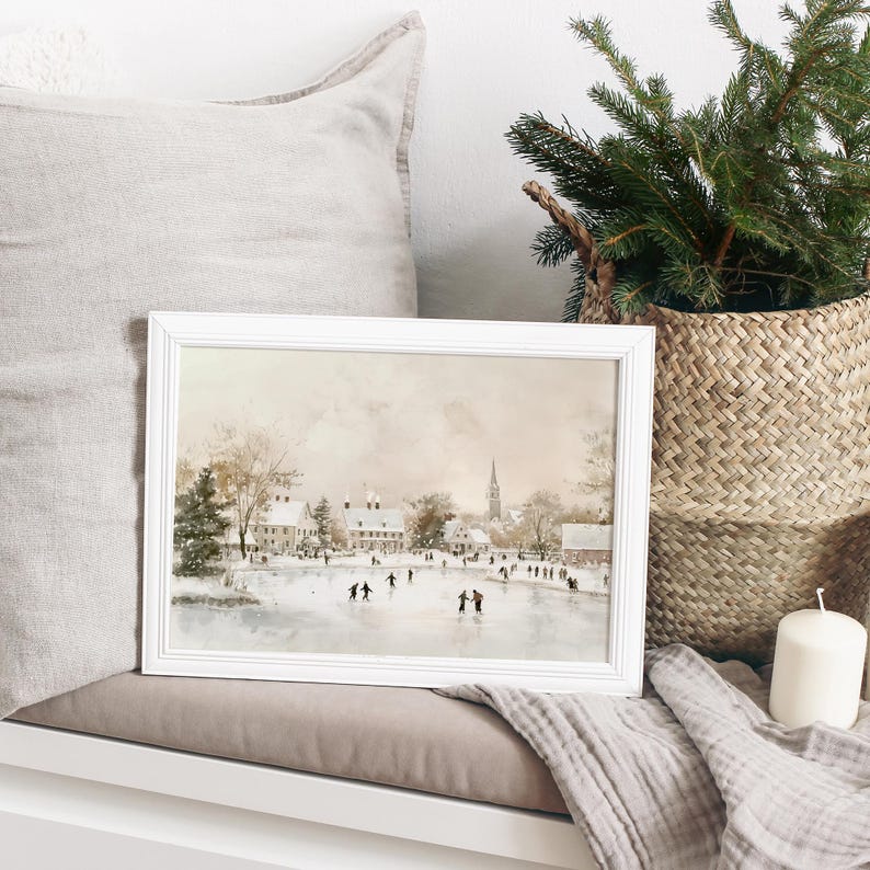 May include: A framed watercolour painting depicting a winter scene with people ice skating on a frozen lake in front of a small town. The painting features a soft, muted colour palette with shades of brown, grey, and white.