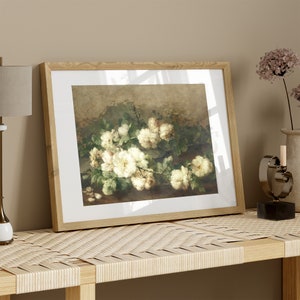 May include: A framed painting of a bouquet of white roses with green leaves on a brown background.