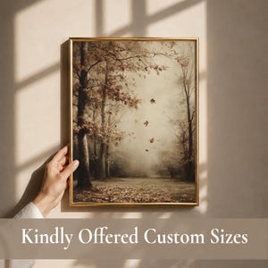 May include: A rectangular wall art print in a thin gold frame featuring a sepia-toned forest scene with bare trees, fallen leaves on the ground, and several leaves drifting through the air. The artwork displays a muted, earthy color palette.