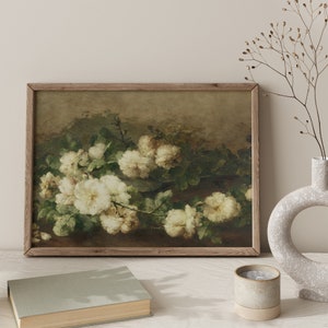 May include: A framed vintage painting of white roses with green leaves on a brown background.