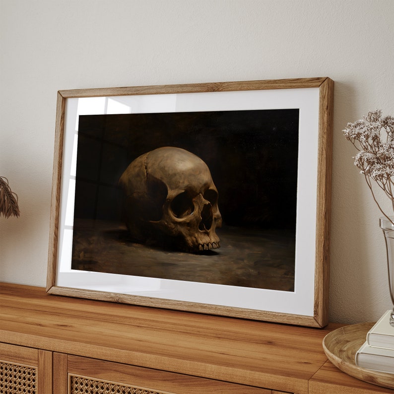 May include: A framed print of a still life featuring a human skull in a dark setting. The skull is positioned on a surface and is the focal point of the image.