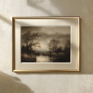 May include: A framed landscape print featuring a sepia-toned scene of trees along a calm river under a cloudy sky. The artwork is encased in a metallic gold frame with a wide, cream-colored mat board, creating a classic presentation for the wall.