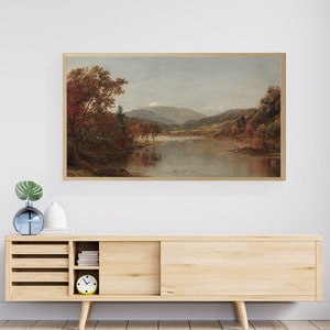 Puede incluir: Una pintura de paisaje enmarcada que representa un r&iacute;o que fluye a trav&eacute;s de un valle con monta&ntilde;as en el fondo. Los &aacute;rboles est&aacute;n en colores oto&ntilde;ales, con tonos de rojo, naranja y amarillo.