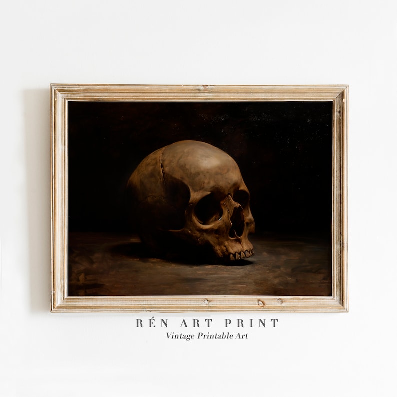 May include: A vintage art print of a human skull in a dark brown frame. The skull is painted in a realistic style and is positioned on a dark brown surface. The print is titled "R&Eacute;N ART PRINT" and "Vintage Printable Art".
