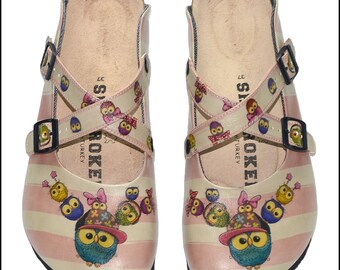 May include: Pair of pink and white striped clogs with owl graphics. The clogs have a cross-strap design with owl patterns and adjustable buckles. The footbed is a light tan color, and the clogs are marked with the number 37.