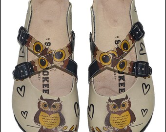 May include: A pair of beige slip-on sandals with an owl print. The sandals have two black straps with buckles and the text "SOKEE TURKEY" on the insole.