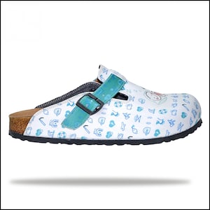 May include: White clog with a blue and green strap and a cork sole. The clog is covered in a pattern of small blue icons.