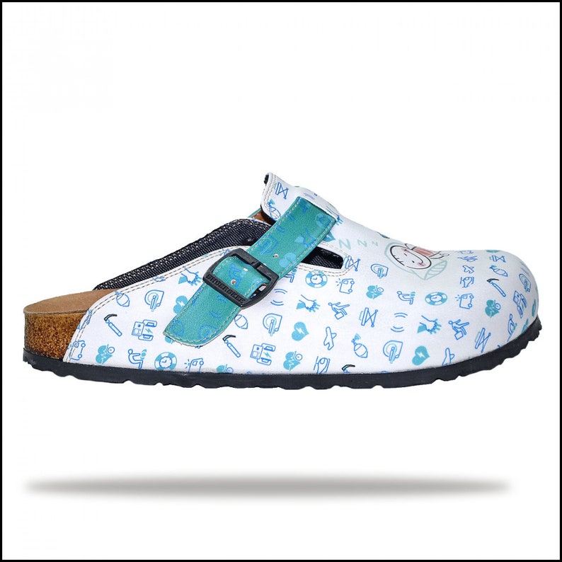 May include: White clog with a blue and green strap and a cork sole. The clog is covered in a pattern of small blue icons.