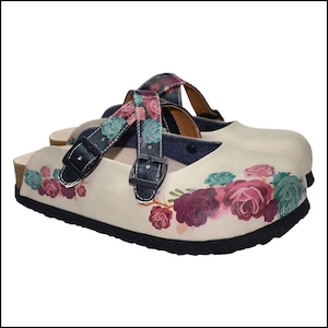 May include: Cream-colored clogs with a floral design featuring pink, burgundy, and teal roses. The clogs have black soles and straps with buckles. The straps are patterned with the same floral design.