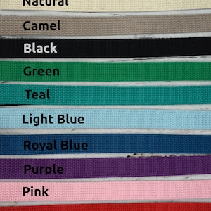 May include: A close-up of a selection of woven fabric straps in various colors. The colors include natural, camel, black, green, teal, light blue, royal blue, purple, pink, and red. Each strap has a label with its color name.