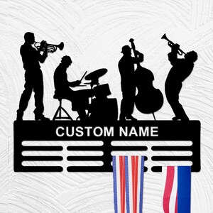 May include: Black metal medal display with a jazz band silhouette, including a trumpet player, a drummer, a bass player, and a saxophonist. The display has a black metal bar with the text "CUSTOM NAME" and 10 slots for medals. Two red, white, and blue striped ribbons are hanging from the display.