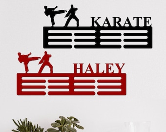May include: Black and red metal medal display with karate silhouettes. The top display has the word "KARATE" and the bottom display has the name "HALEY".