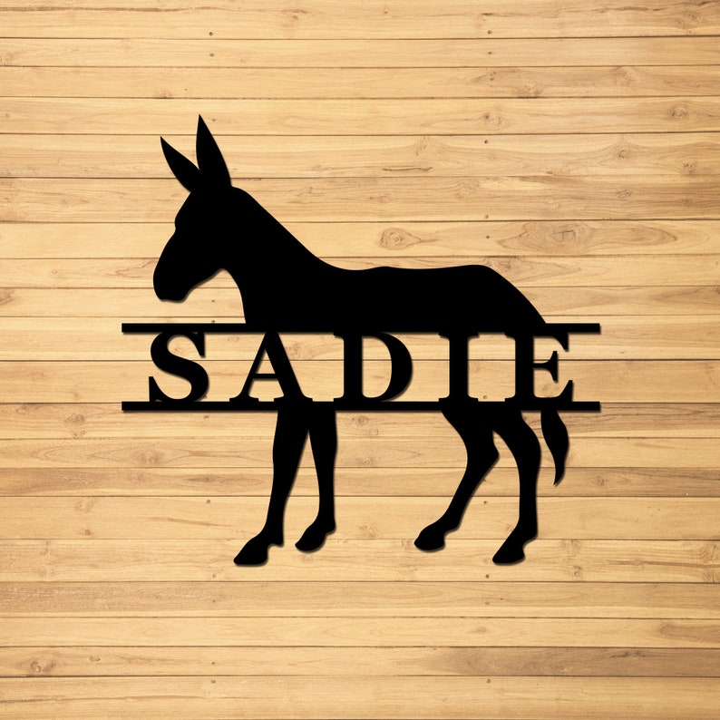 May include: Black silhouette of a donkey with the name "SADIE" in a split-style design. The name is centered on the donkey's body, with a line above and below the name.