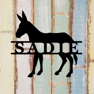 May include: Black silhouette of a donkey with the name "SADIE" in a double line across the middle of the animal.