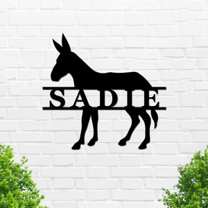 May include: Black metal silhouette of a donkey with the name "SADIE" split in half above and below the animal.