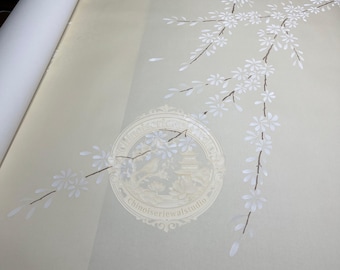 May include: A roll of light beige wallpaper featuring a white cherry blossom branch pattern. A circular watermark with the text Chinoiseriewallstudio is visible in the center, depicting a pagoda, a bird, and lotus flowers in a light cream tone.