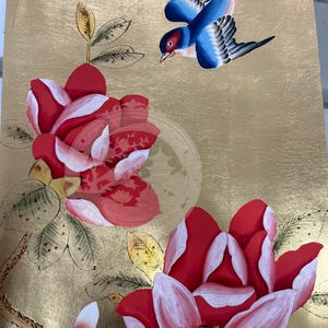 May include: A painting on a gold background featuring two large red and white flowers with green leaves on a brown branch and a blue bird with black wings flying above. A circular watermark with a pagoda icon is visible in the center.