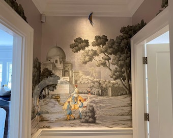 Puede incluir: Un pasillo con un mural que representa un paisaje oriental con un camello y figuras. El mural está en tonos grises, beige y marrón, con un edificio con cúpula y árboles. Una decoración de pájaro azul y amarillo está fijada al techo.