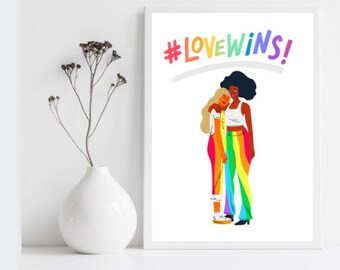 May include: A white framed print with a rainbow-colored hashtag that says "#LOVEWINS!" Two women are standing together, one with brown hair and one with black hair. They are both wearing rainbow-colored pants and smiling.