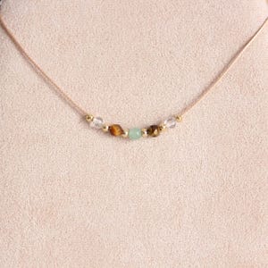 May include: A delicate gold necklace with a string of clear, brown, and green gemstone beads.