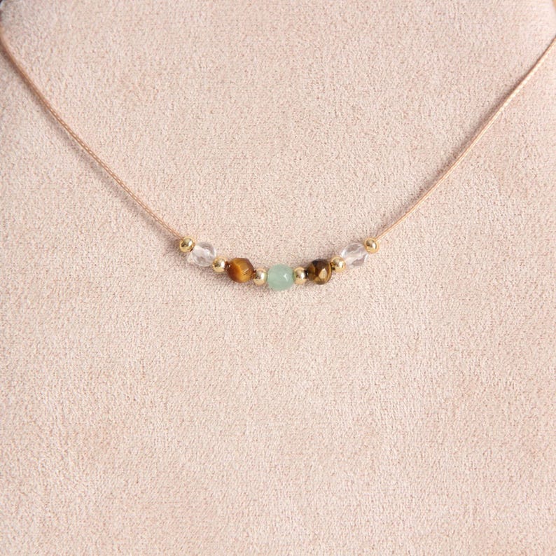 May include: A delicate gold necklace with a string of clear, brown, and green gemstone beads.