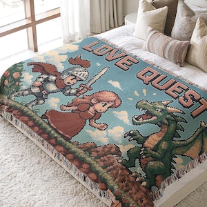 Könnte beinhalten: Eine Decke mit Pixel-Design und den Worten "LOVE QUEST" in Rosa. Die Decke zeigt einen Ritter, eine Prinzessin und einen grünen Drachen. Die Decke hat einen Fransenrand und wird auf einem Bett mit Kissen präsentiert.