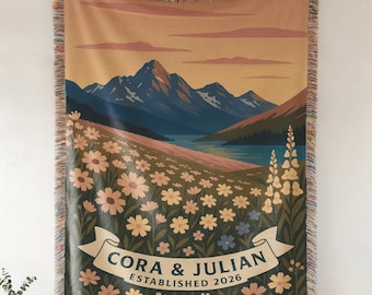 May include: Woven tapestry blanket featuring a scenic landscape with mountains, a lake, and a field of flowers. The blanket has a banner with the names "CORA & JULIAN" and "ESTABLISHED 2026". The Cool Ruler Co. logo is at the bottom.