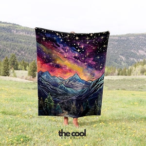 May include: A colourful throw blanket featuring a mountain range and starry night sky design. The blanket is made from soft, plush fabric and has a watercolour-like style.