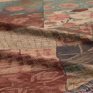 May include: A woven tapestry throw blanket with a patchwork design featuring various colours and patterns, including red, blue, green, and beige. The blanket has a fringed edge.