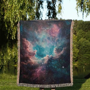 May include: A woven tapestry throw blanket featuring a colorful nebula with stars and a dark blue background.