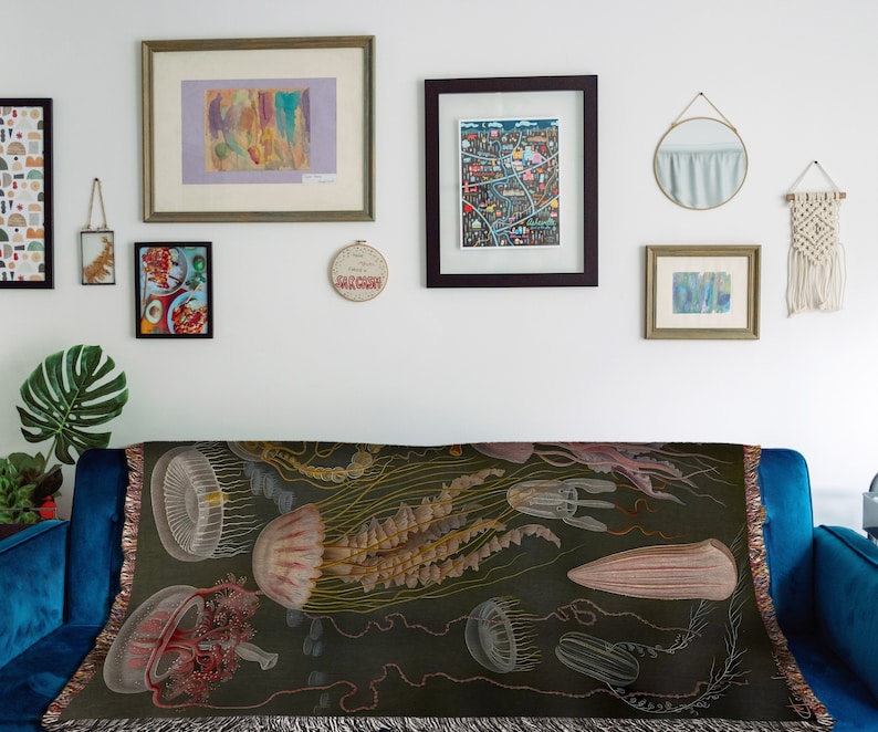 May include: A tapestry throw blanket with a dark green background featuring a vintage illustration of jellyfish in shades of pink, white, and brown.