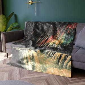 May include: A black and gold throw blanket with a colorful abstract design. The design features a galaxy with streaks of color and a waterfall.