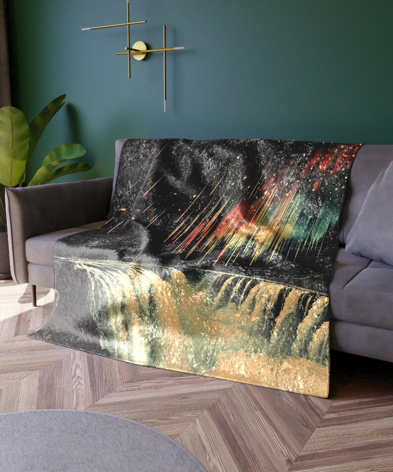 May include: A black and gold throw blanket with a colorful abstract design. The design features a galaxy with streaks of color and a waterfall.