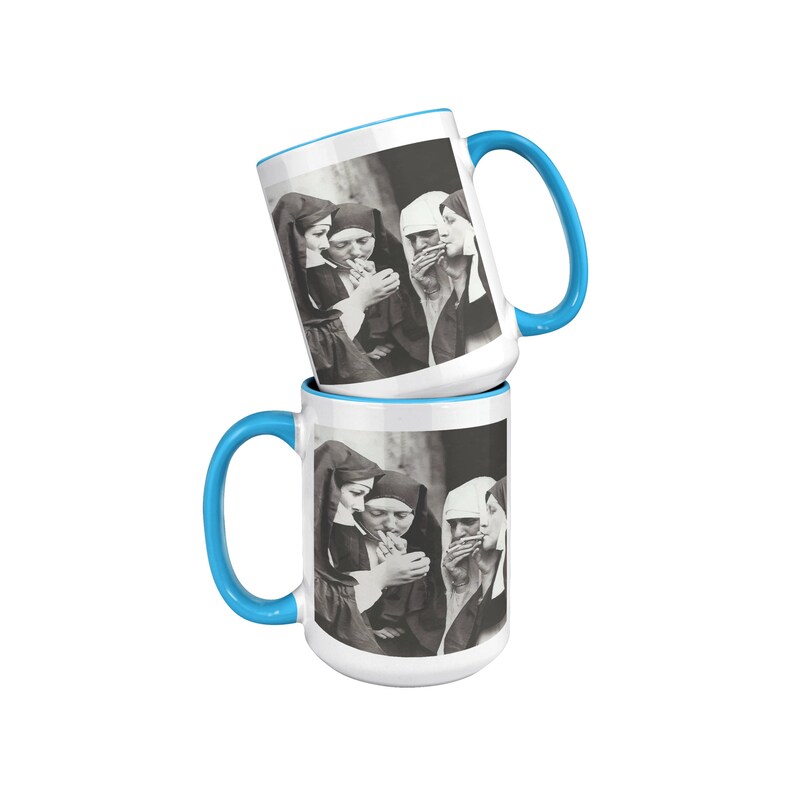 May include: Two white ceramic mugs with blue rims, each featuring a black and white photo of three nuns smoking cigarettes. The mugs are stacked on top of each other.