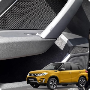 Può includere: Un SUV Suzuki Vitara giallo con tetto nero. L'immagine mostra il pannello interno della portiera dell'auto, con una superficie grigia strutturata, una griglia dell'altoparlante nera e una maniglia argentata.