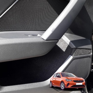 Pode incluir: Interior da porta do carro com painel cinza, alto-falante, controles de janela e puxador prateado. O painel da porta tem uma capa de alto-falante de malha preta. Um carro laranja está em primeiro plano.