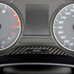 Puede incluir: Primer plano del salpicadero de un coche con una moldura de fibra de carbono negra y gris. El salpicadero cuenta con una pantalla digital con fondo negro y un veloc&iacute;metro con una esfera blanca y n&uacute;meros negros. El veloc&iacute;metro marca 0.0/SET.