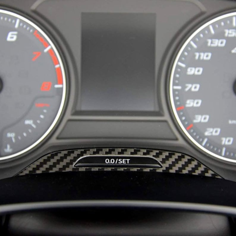 Puede incluir: Primer plano del salpicadero de un coche con una moldura de fibra de carbono negra y gris. El salpicadero cuenta con una pantalla digital con fondo negro y un veloc&iacute;metro con una esfera blanca y n&uacute;meros negros. El veloc&iacute;metro marca 0.0/SET.