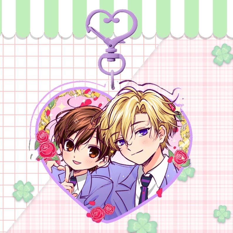 May include: A heart-shaped charm featuring two anime characters, framed by roses, with a lavender-colored heart-shaped clasp. The charm has a pink and white checkered background with green clovers.
