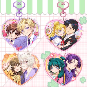 May include: Four heart-shaped anime character keychains. Each keychain features a different couple, with vibrant colors and detailed artwork. The keychains have a heart-shaped clasp at the top, and are perfect for fans of anime and manga.