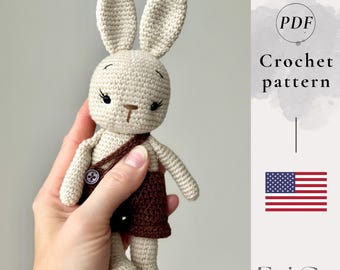 May include: A crocheted bunny doll in beige with brown shorts and a matching satchel. The doll has long ears, a button on the satchel, and delicate facial features. The image includes the text "Crochet pattern" and the American flag.