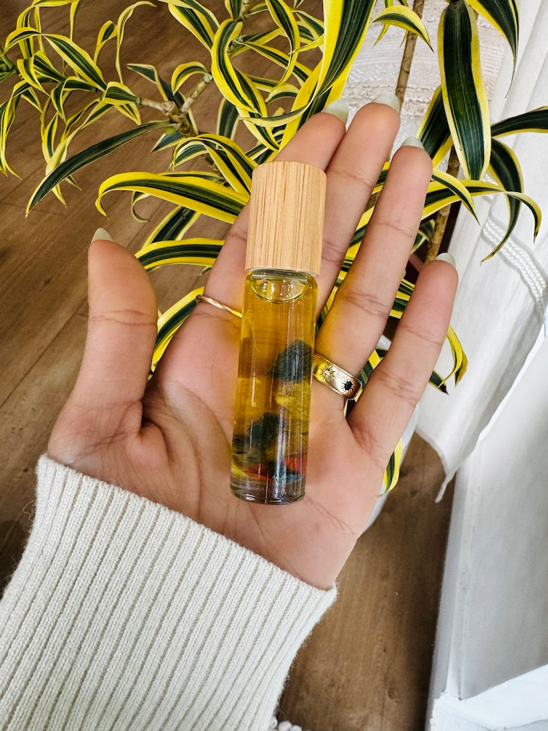 Pu&ograve; includere: Un flacone di vetro trasparente con tappo in legno, riempito di un liquido giallo e piccole pietre colorate. Il flacone &egrave; tenuto in una mano.