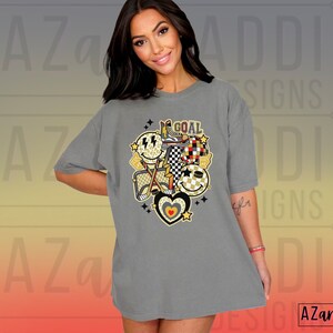 May include: Gray oversized t-shirt with a graphic design of hockey equipment, smiley faces, and the word "GOAL".