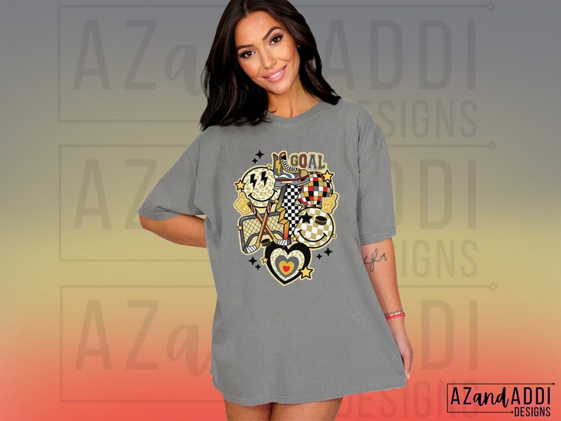 May include: Gray oversized t-shirt with a graphic design of hockey equipment, smiley faces, and the word "GOAL".