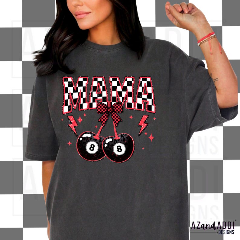 May include: A black t-shirt with the word "MAMA" in white letters with a checkered pattern. The word is above a red bow with two cherries with 8-ball designs.