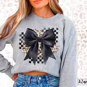 May include: A gray sweatshirt with a black bow and a leopard print design on a checkered background.