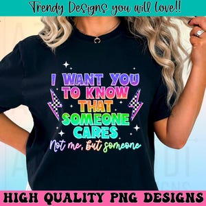May include: Black t-shirt with the text "I WANT YOU TO KNOW THAT SOMEONE CARES" in a colorful, rainbow-like font. The design includes lightning bolts with checkered patterns. The phrase "Not me, but someone" is written below. The shirt also has the text "HIGH QUALITY PNG DESIGNS".
