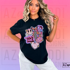 May include: Black t-shirt with a graphic design featuring a smiley face, a butterfly, a disco ball, a heart, and the text "Gymnastics".