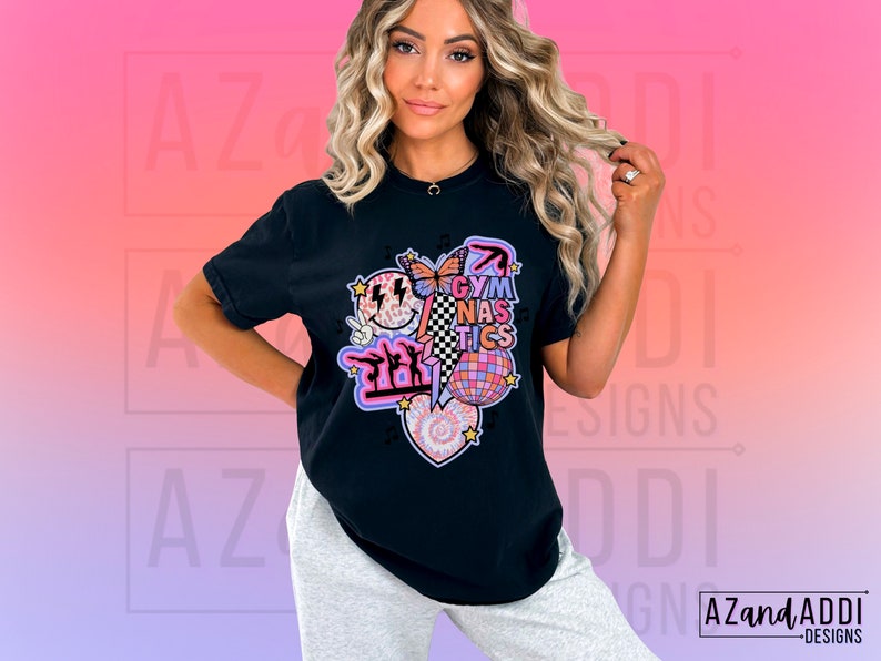 May include: Black t-shirt with a graphic design featuring a smiley face, a butterfly, a disco ball, a heart, and the text "Gymnastics".